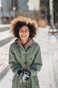 Woman smiling while playing in snow wearing Nöz sunscreen in orange on her nose