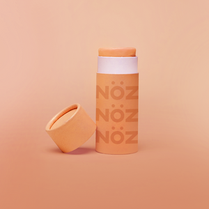 Nöz sunscreen in bright orange color displayed in sustainable paper tube packaging 